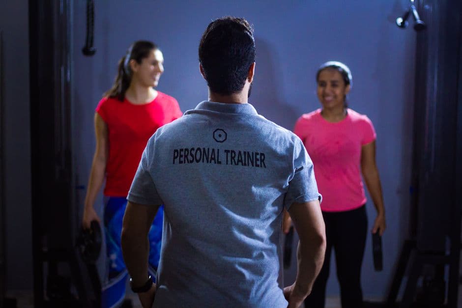 Personal trainer coaching two clients in a gym