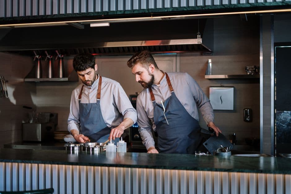Two chefs plating dishes at a restaurant counter